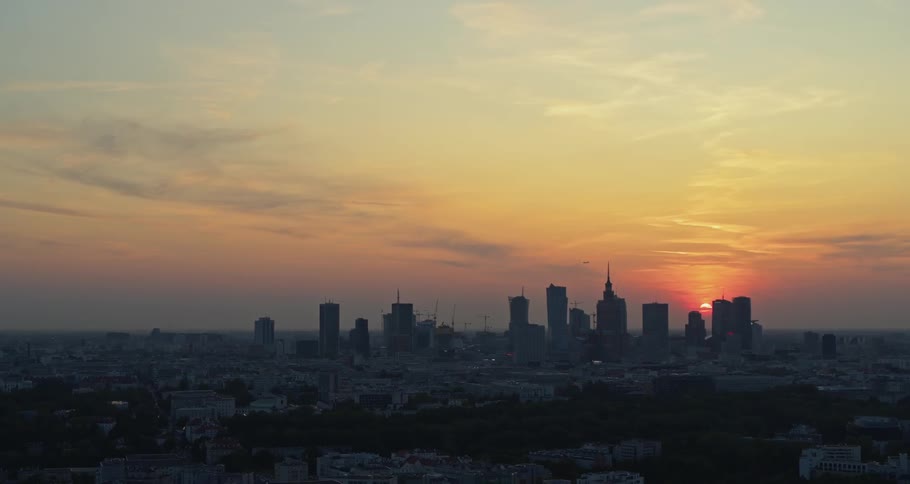 The sun sets behind skyscrapers in a city skyline