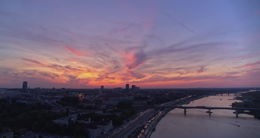 A city sprawls next to a river at dusk or dawn