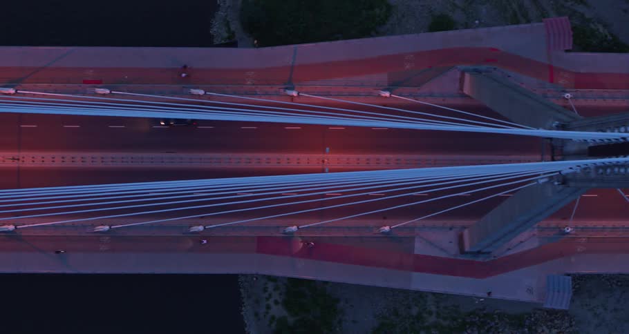 A bridge with four traffic lanes and a bike path from above at night