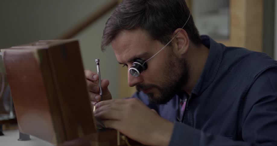 Man wearing an eye piece works on a small object