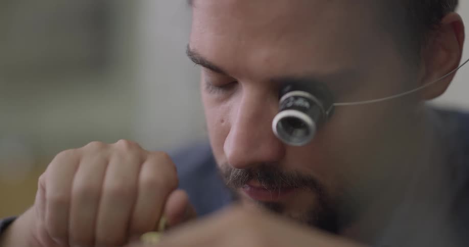 A craftsman wearing a watchmakers loupe turns a key to make a repair