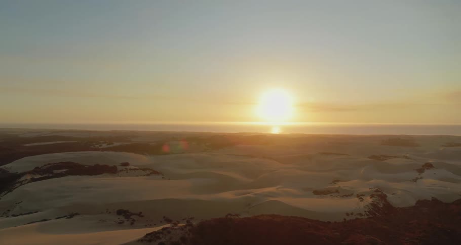 Sun hovers on horizon over snow covered terrain