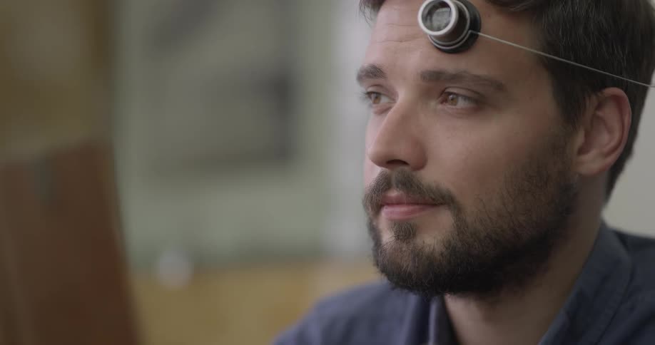 A man is examining something with a small lens