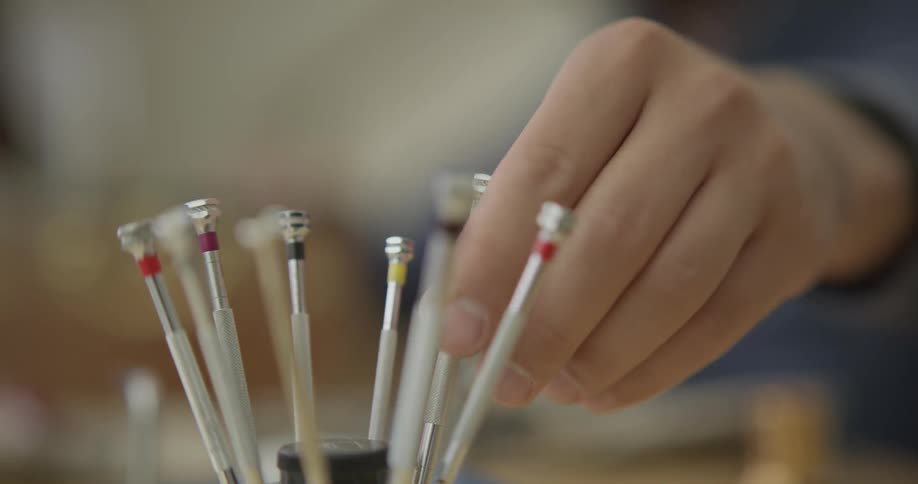 A person taking a screwdriver from a cup of precision screwdrivers