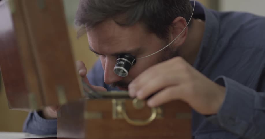 A man using a head mounted loupe to examine the contents of a box
