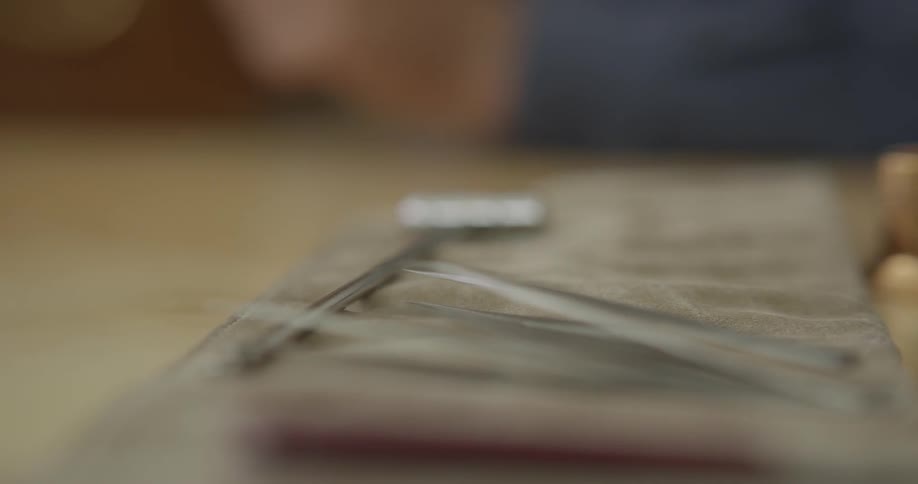 A man picks a tool up from a table and then puts it back down