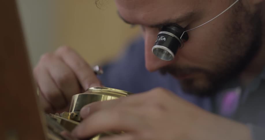 Man wearing an eye piece works on a device with a screwdriver