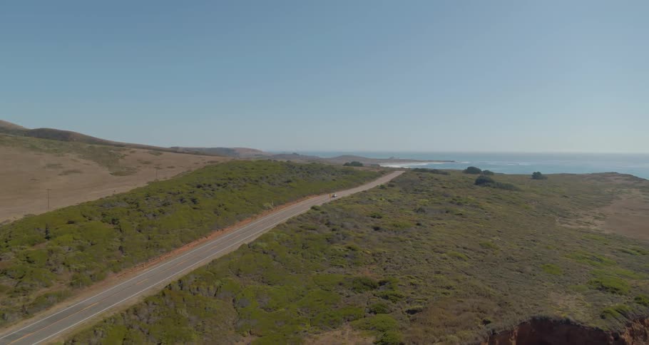 Cars are driving on a road in a rural area