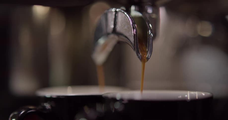 Coffee drips from a spout into a cup below