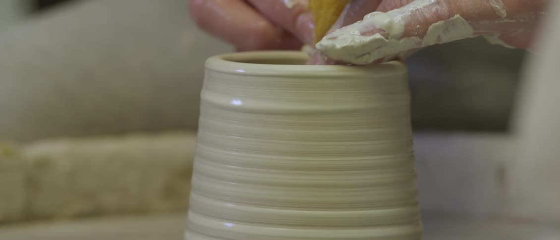 Person molding clay while it's spinning in front of them