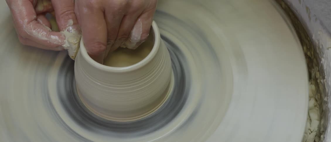 A person is spinning clay to form an object