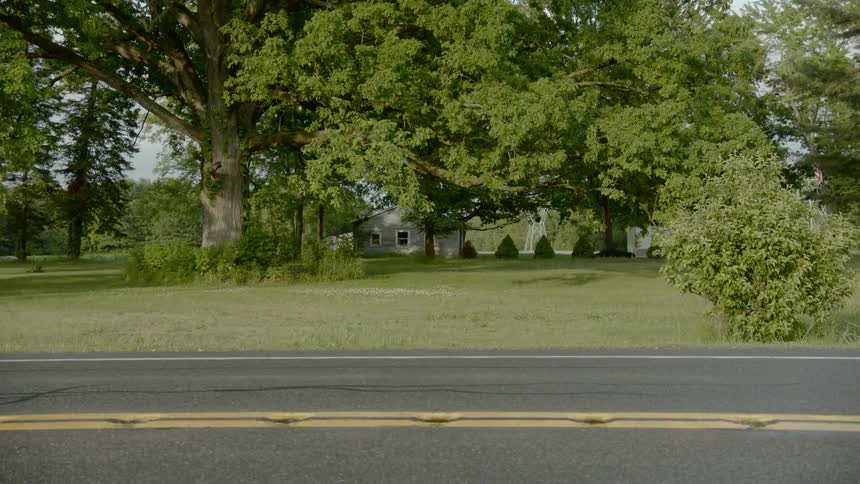 Car driving on neighborhood road passes in front of the camera