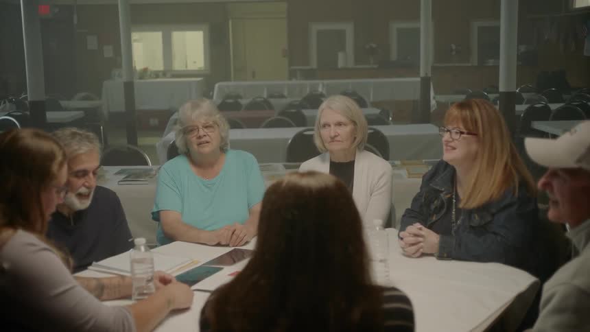 A group of people talking while sitting around a round table