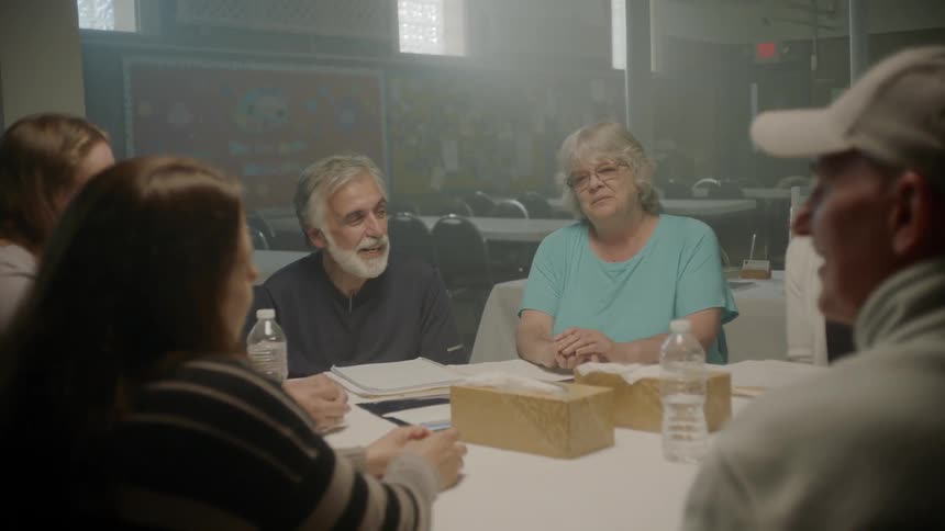 Five people sit around a table talking