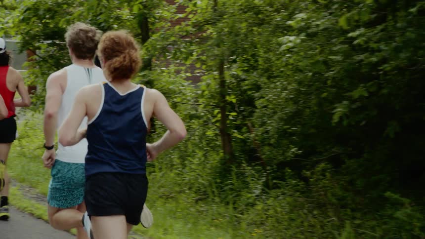 Men and women run on a trail near the trees