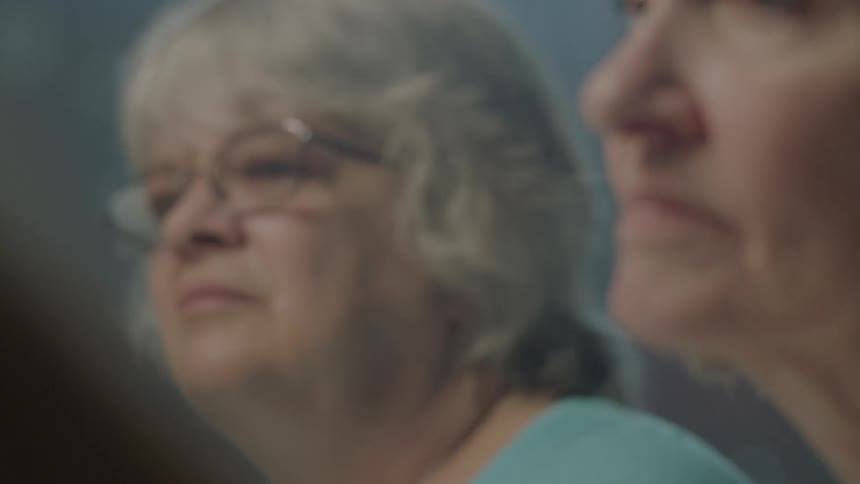 Two women sitting one with glasses one without