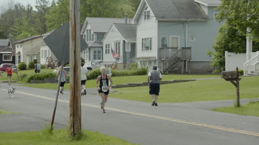 People running a long a road with running bibs on