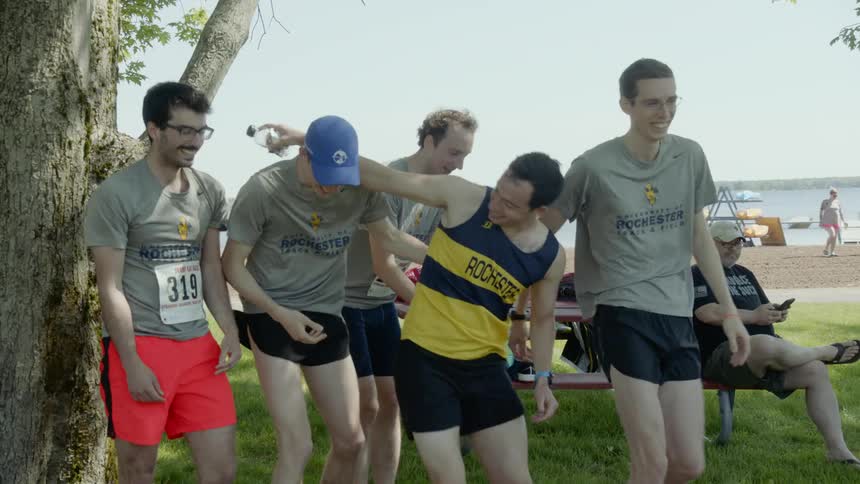 A group of young men hold another man in their arms and toss him in to the air