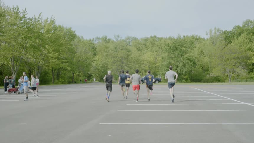 A group of young men run through a parking lot