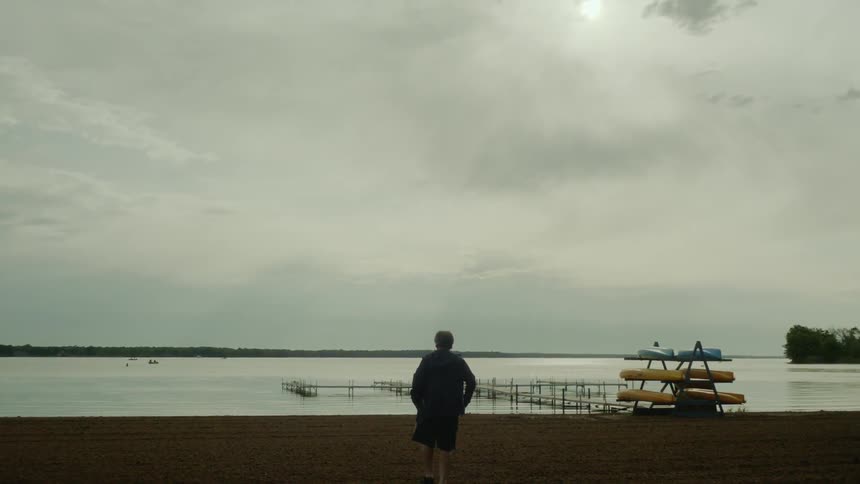 A man walks towards the ocean at sunset