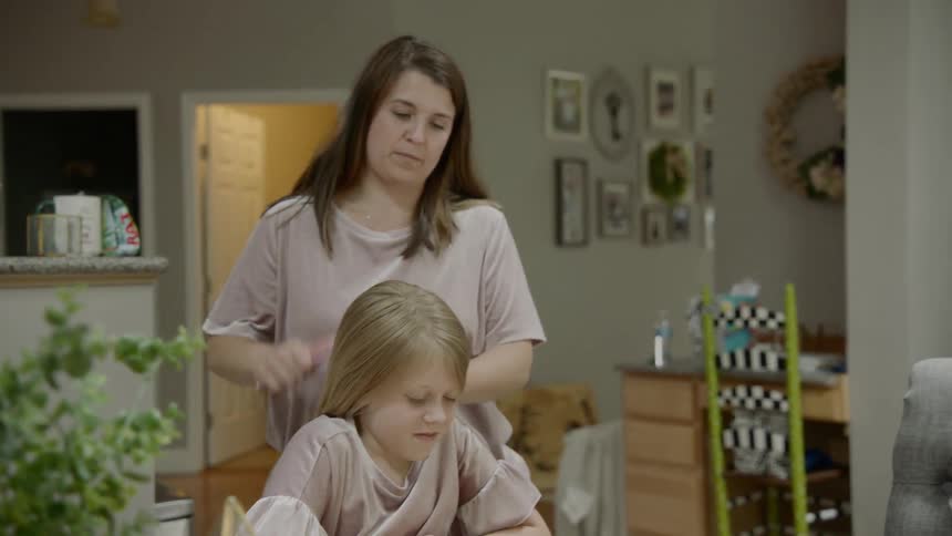A woman brushes a young girls hair