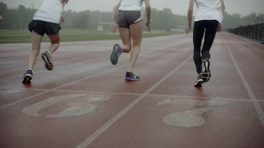 Track runners taking off from start line on a track in early morning