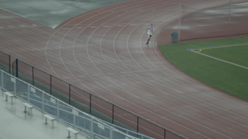 A man in a track uniform running along an athletics track
