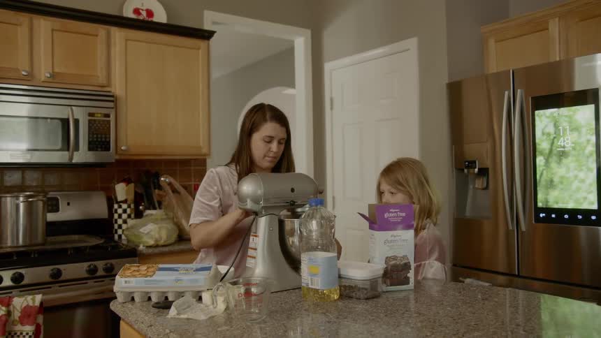 A mother sets up a mixing bowl while her daughter watches