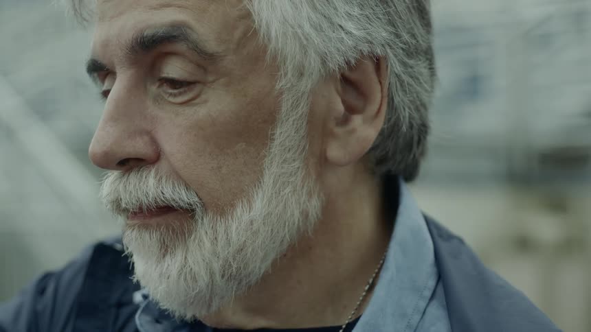 An elderly man sits and looks in to the distance