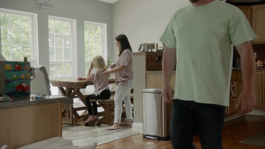 A woman brushing a girls hair in a dining room