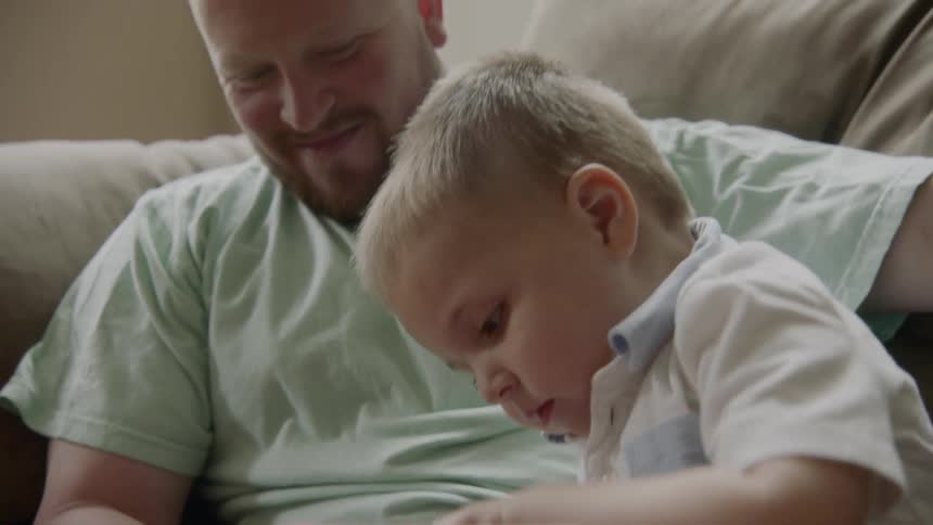 A father shows his son how to use a tablet