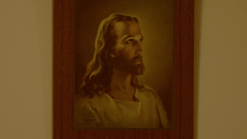 A painting of christ hangs on a wall in a wood frame
