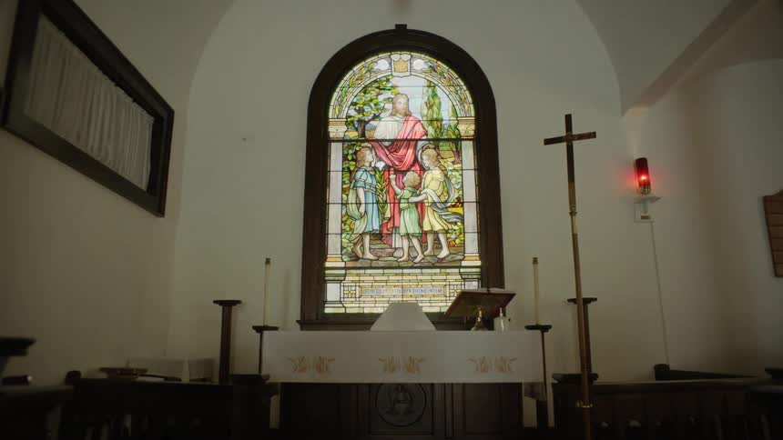 A large stained glass window of a religious scene at the front of a church