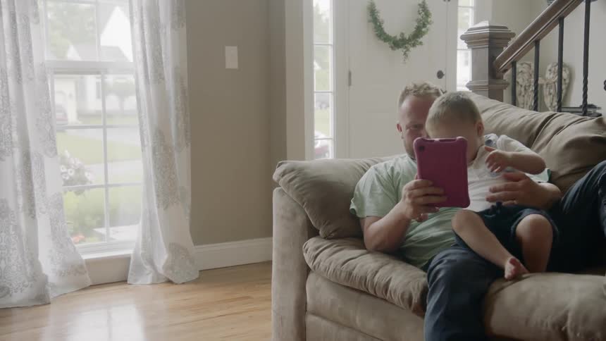 A father and his young male child play with a toy on a couch