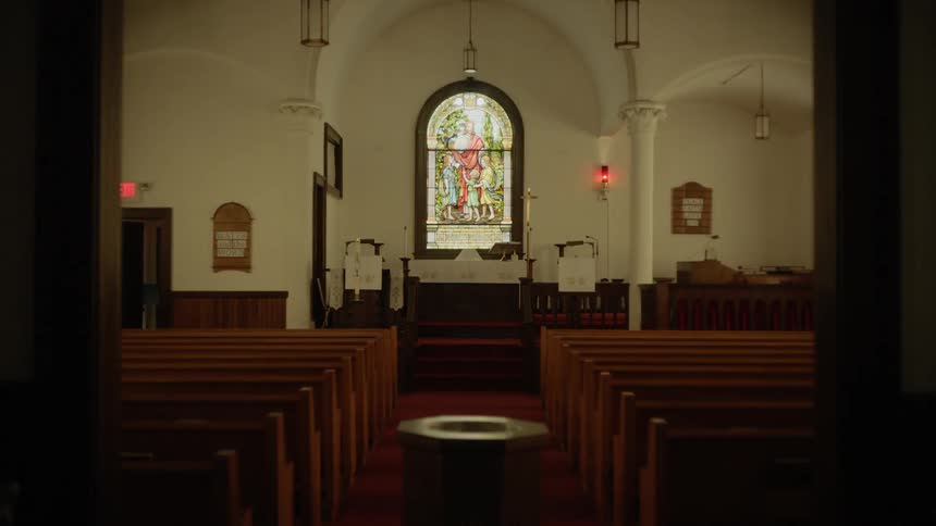 An empty church full of pews and large stained glass window