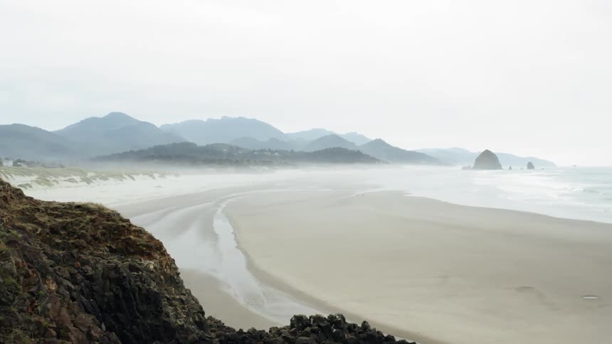 A sandy beach with the ocean and mountains in the background