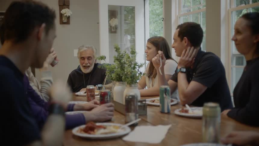 People sitting at the table eat and talk indoors during daylight