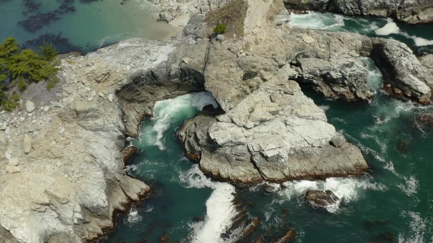 The sea flowing around and under a large rock formation