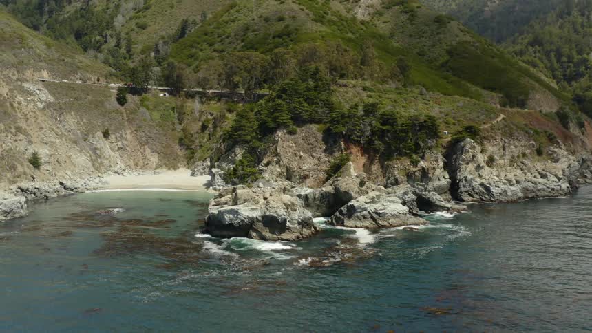 A beach with a rocky shore with mountains in the background
