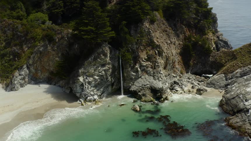 Aerial view of a waterfall on a cliff near ocean