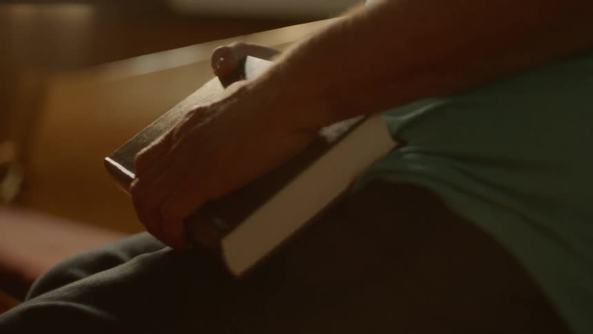 A person sitting in a pew holding on to a bible