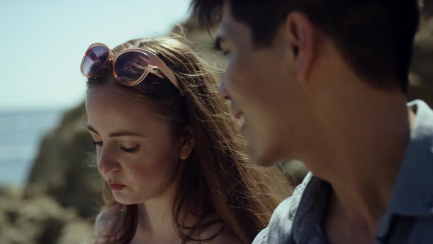 A man and woman talk together by the shore
