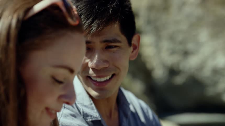 Boyfriend smiling while talking to his girlfriend outdoors