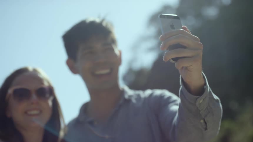 A man and woman take a selfie with a smart phone