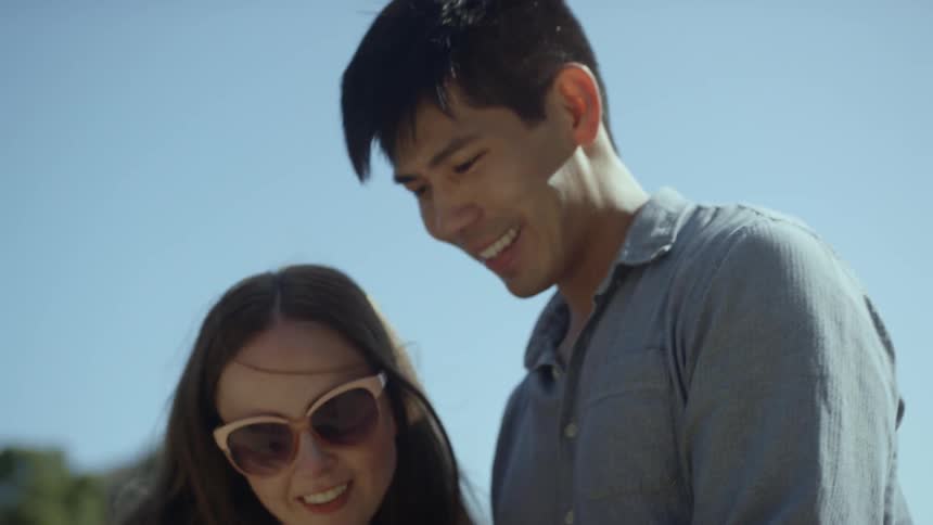 A man and woman standing outside looking at a phone