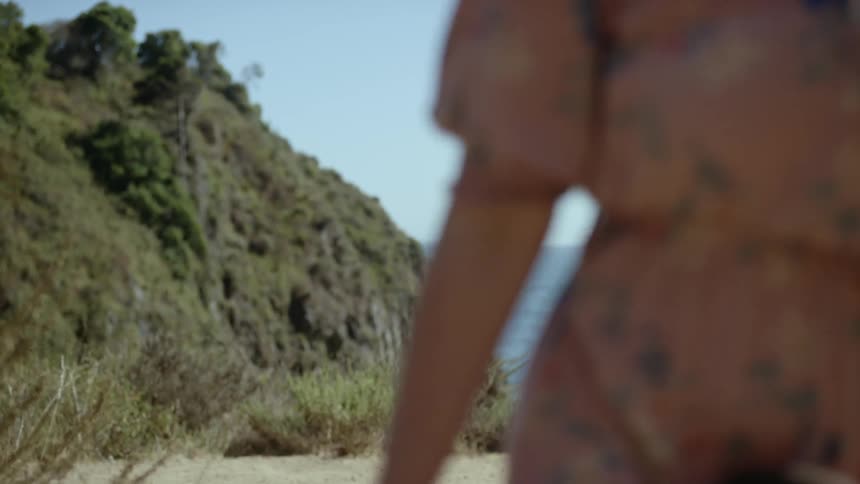 A man and woman walk along the hillside coast line