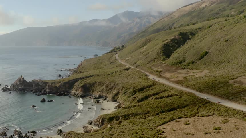 A road between the bottom of a slope and the rocky coastline