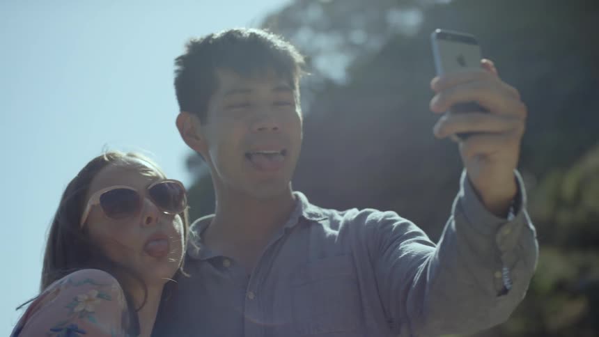 Asian man and white woman take a selfie in the forest during daylight