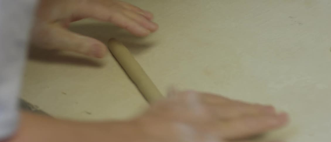 Person rolling dough into a long thin roll