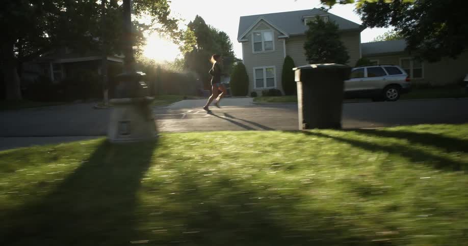 A woman is running down a sidewalk as the sun rises